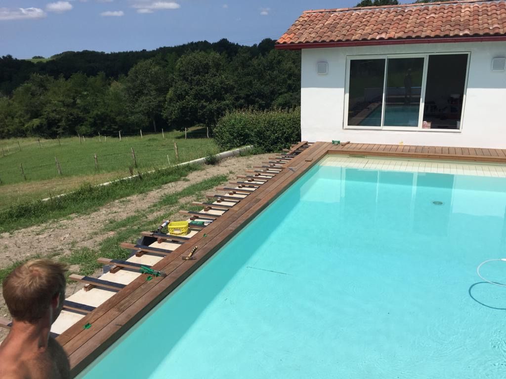 Terrasse en bois en cours de pose au bord d'une piscine